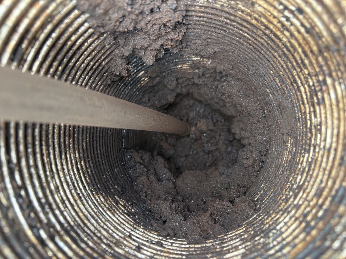 Sweep rod clearing creosote from a flue liner